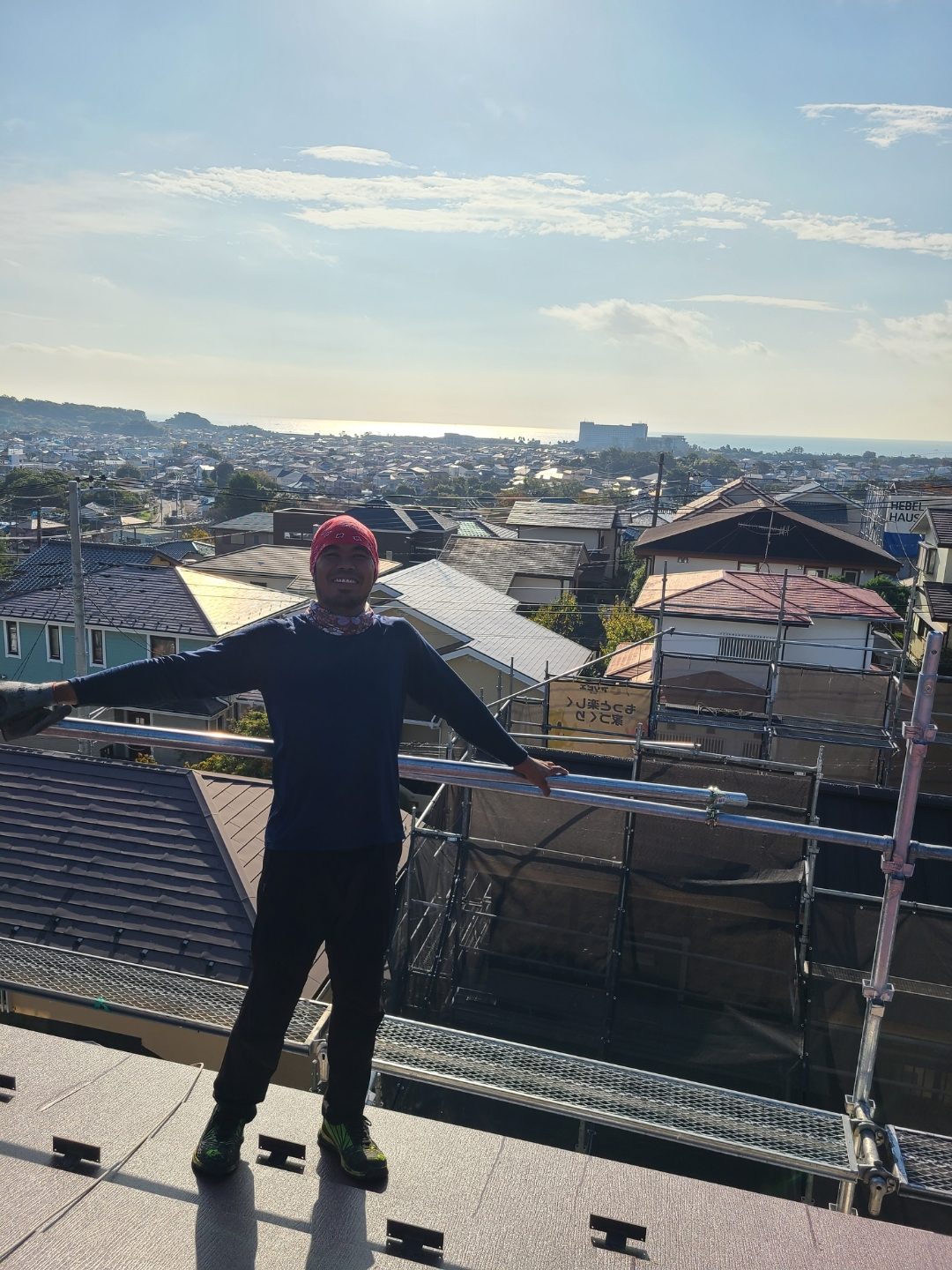 屋根の上で両手を広げる現場スタッフ